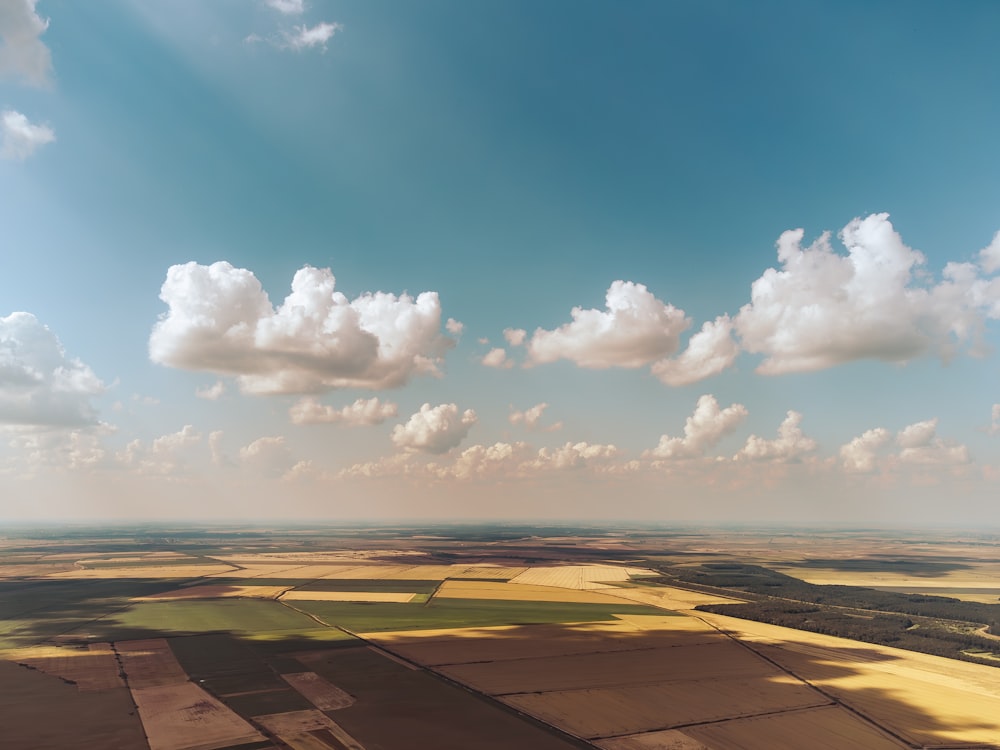 an aerial view of a field with clouds in the sky