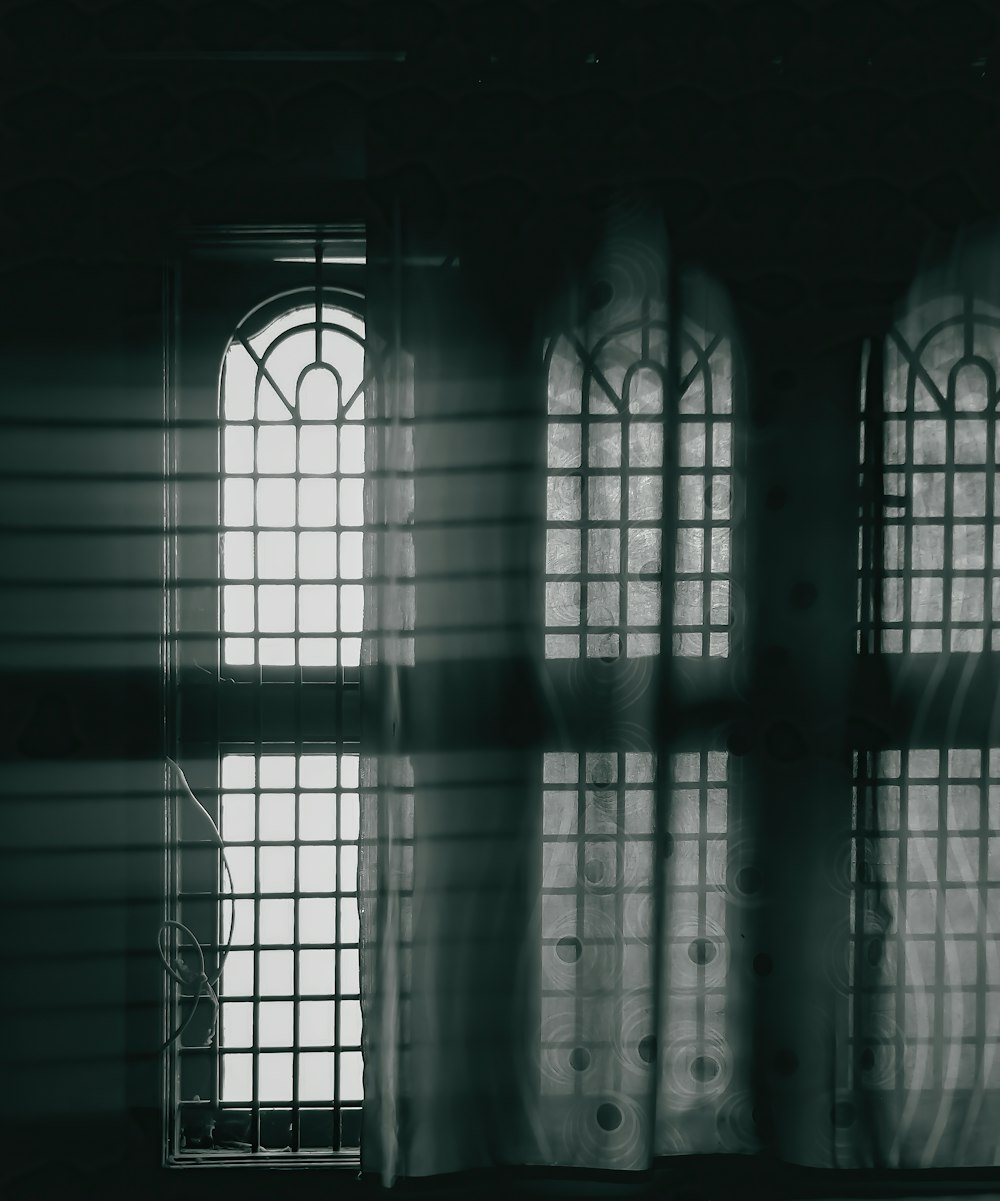 a black and white photo of a window with sheer curtains