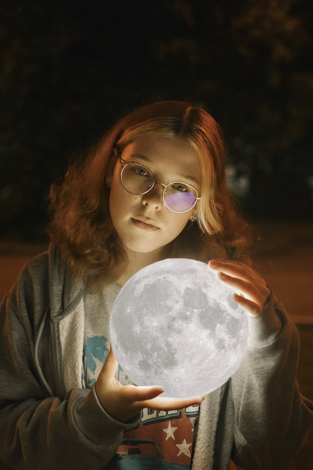 a young girl holding a glowing moon in her hands