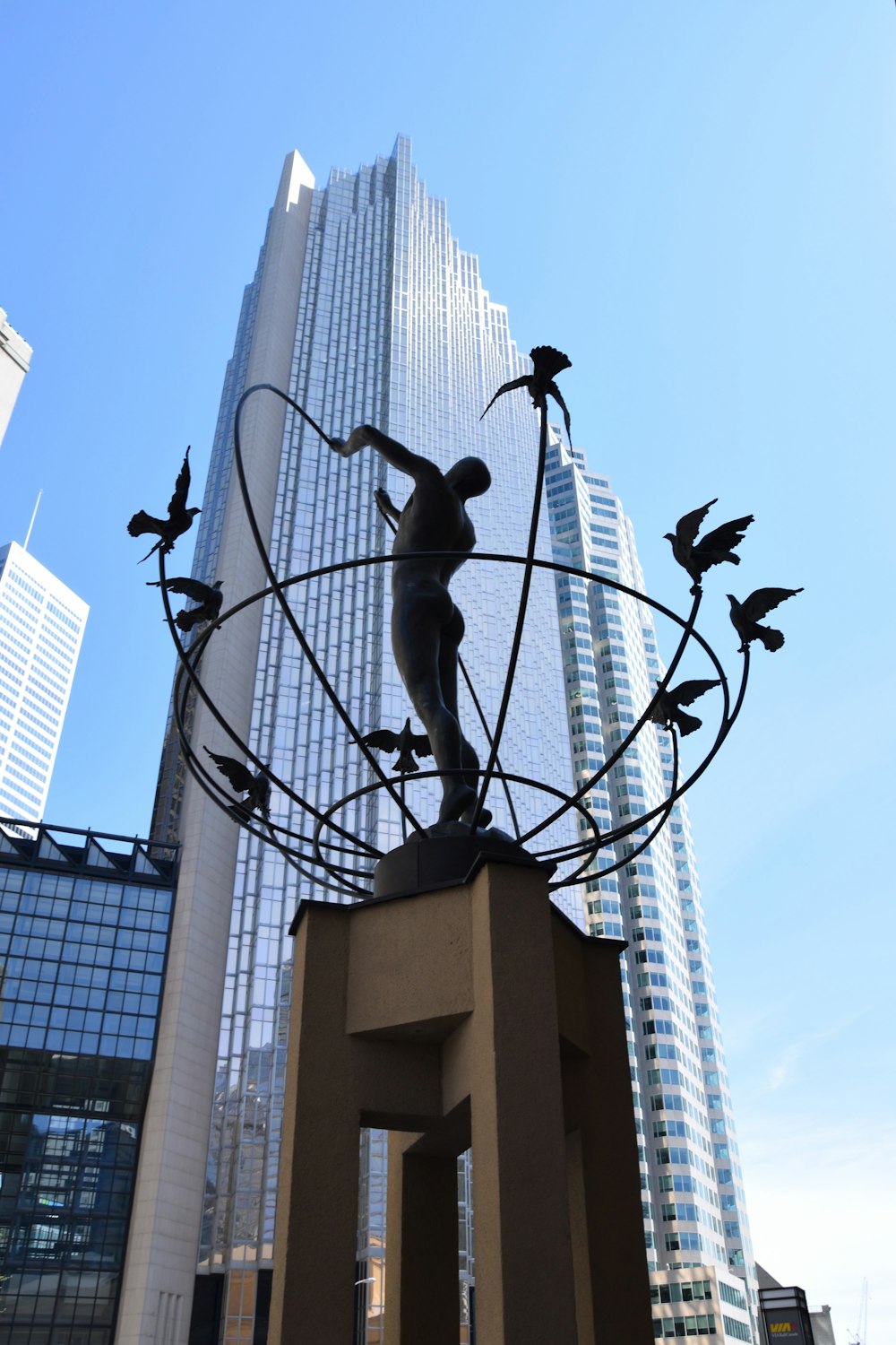 a statue of a man holding a globe in front of a tall building