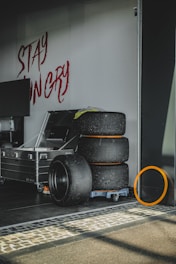 Stack of colorful tires with graffiti art in the background inside a dark garage.