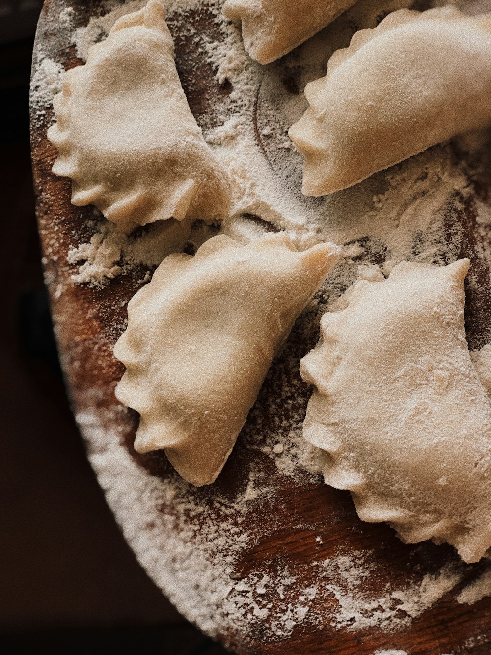 a wooden plate topped with dumplings covered in powdered sugar