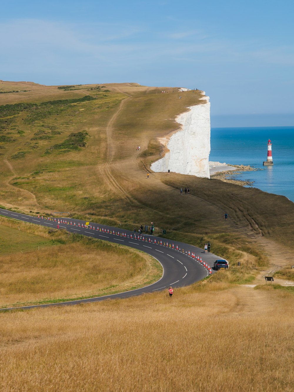 a group of cars driving down a road next to the ocean