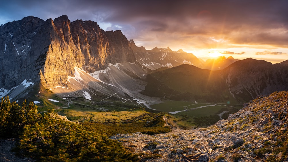 the sun is setting over a mountain range