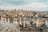 A panoramic view of a cityscape featuring a series of domed rooftops in the foreground, a river with boats in the middle, and a dense array of historic and modern buildings on a hill in the background. The Galata Tower is prominently visible, surrounded by various skyscrapers.