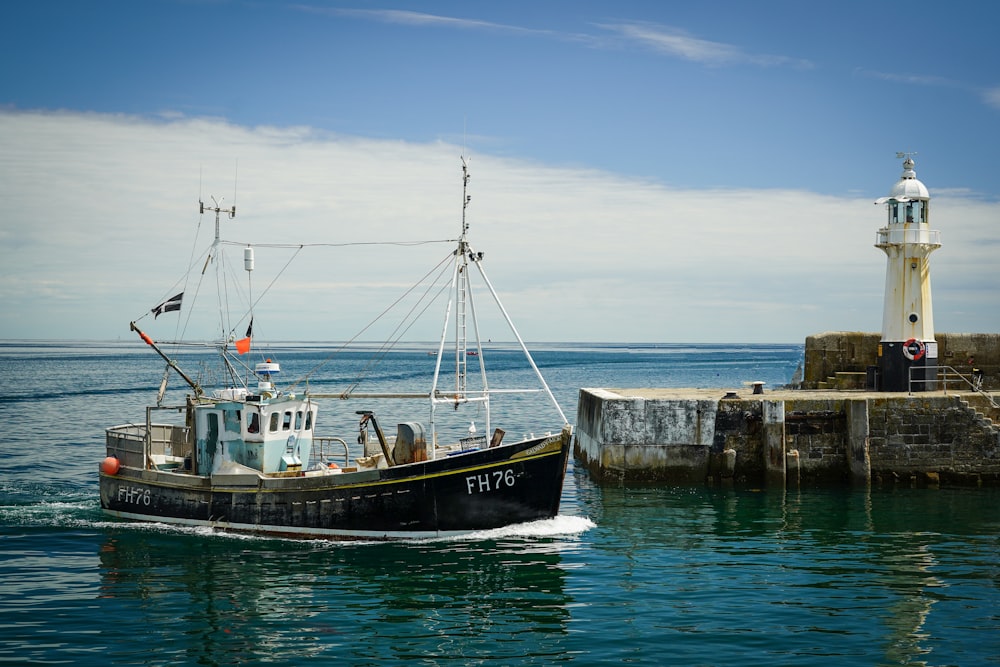 a fishing boat in the water near a light house