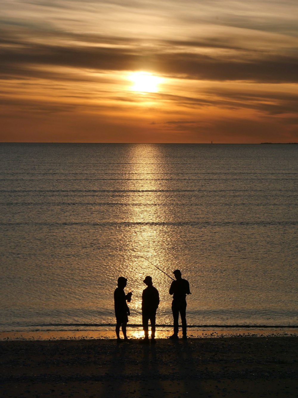 a couple of men standing on top of a beach next to the ocean