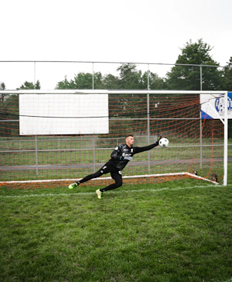 Dynamic shot of a goalkeeper catching the ball mid-air with neon green highlights.