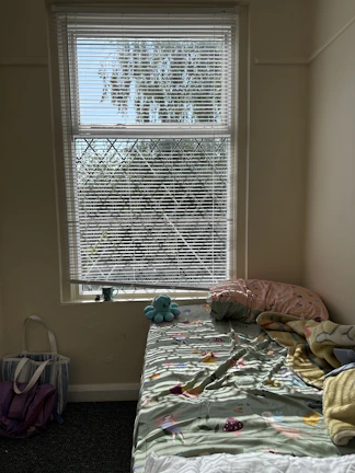 A cozy bedroom corner featuring a soft fabric storage bag filled with blankets.