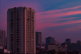 Elegant high-rise apartment building overlooking a city skyline at dusk.