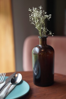 A bright bottle of fabric softener with fresh flowers around it on a wooden table.