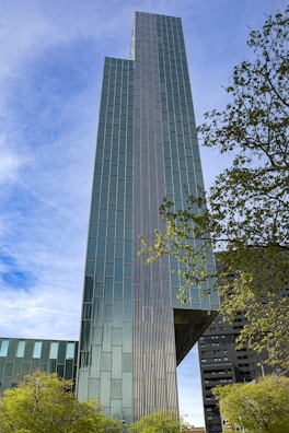a very tall building sitting next to a lush green forest