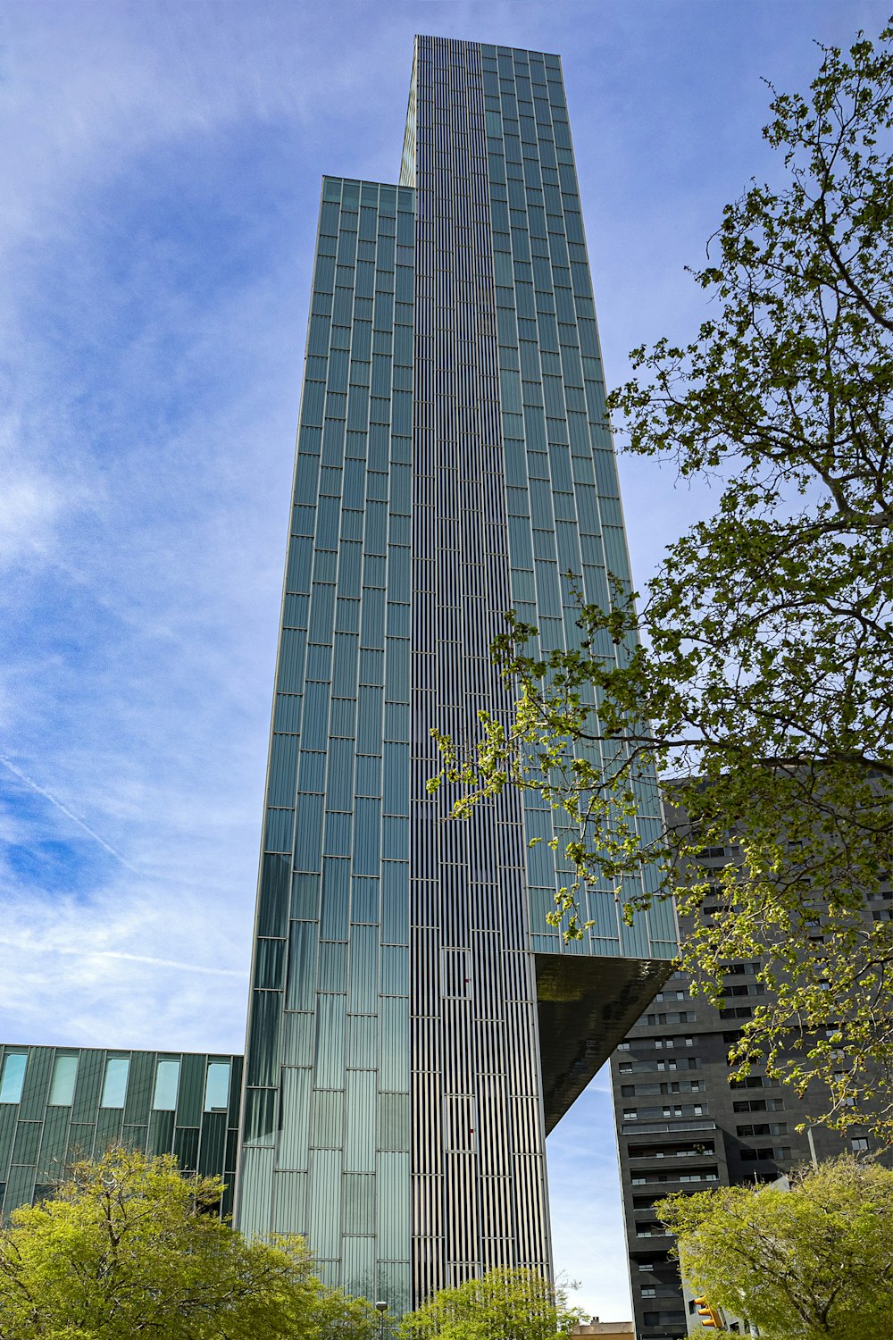 a very tall building sitting next to a lush green forest