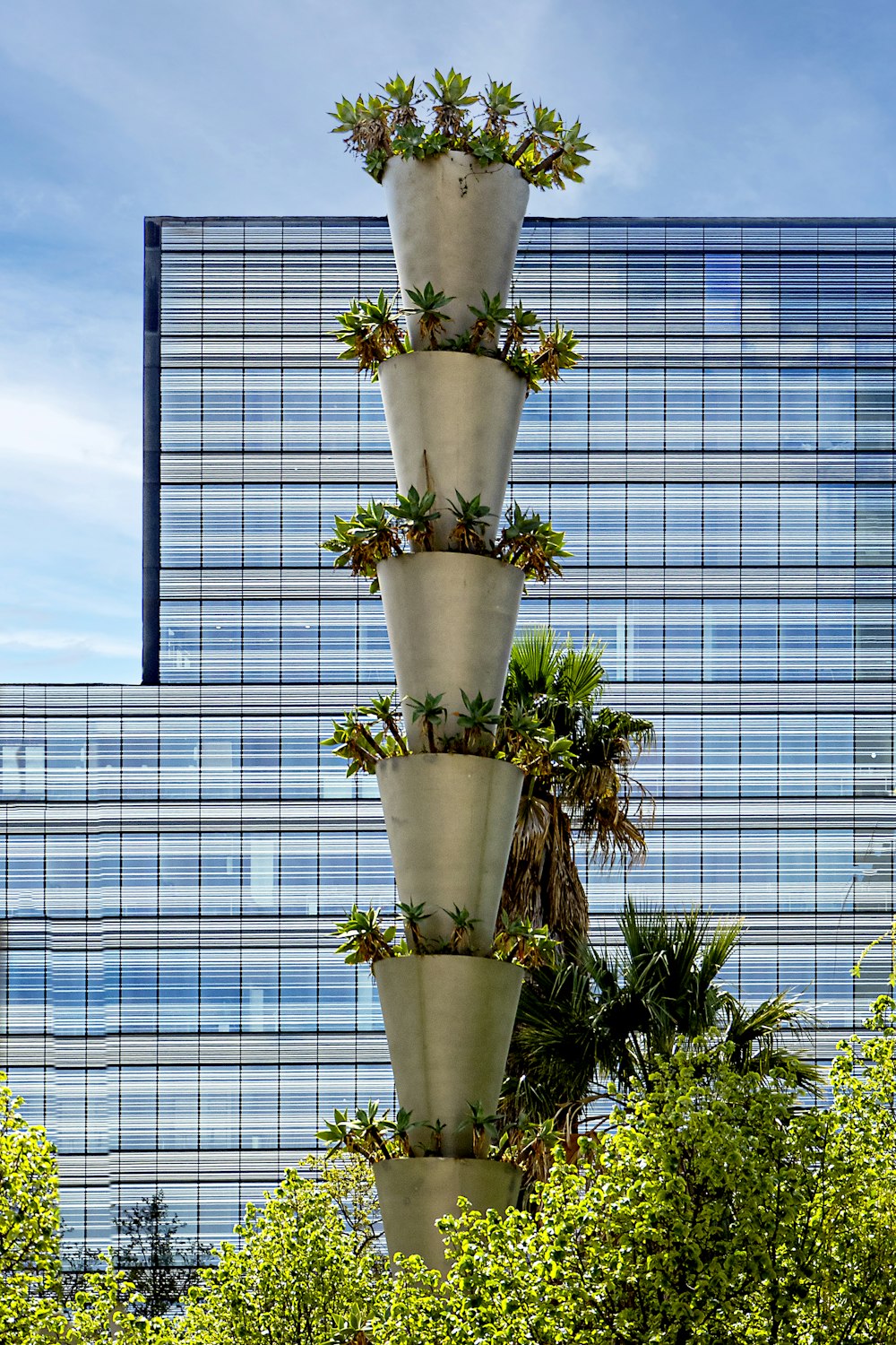 a tall tower of plants in front of a building
