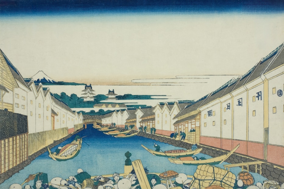 A traditional Japanese ukiyo-e style print depicting a canal lined with warehouses on both sides. Several small boats float on the water, with people engaging in activities along the banks. In the background, mountaintops are visible against a clear sky.