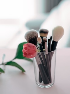 a glass filled with makeup brushes on top of a table