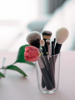 a glass filled with makeup brushes on top of a table