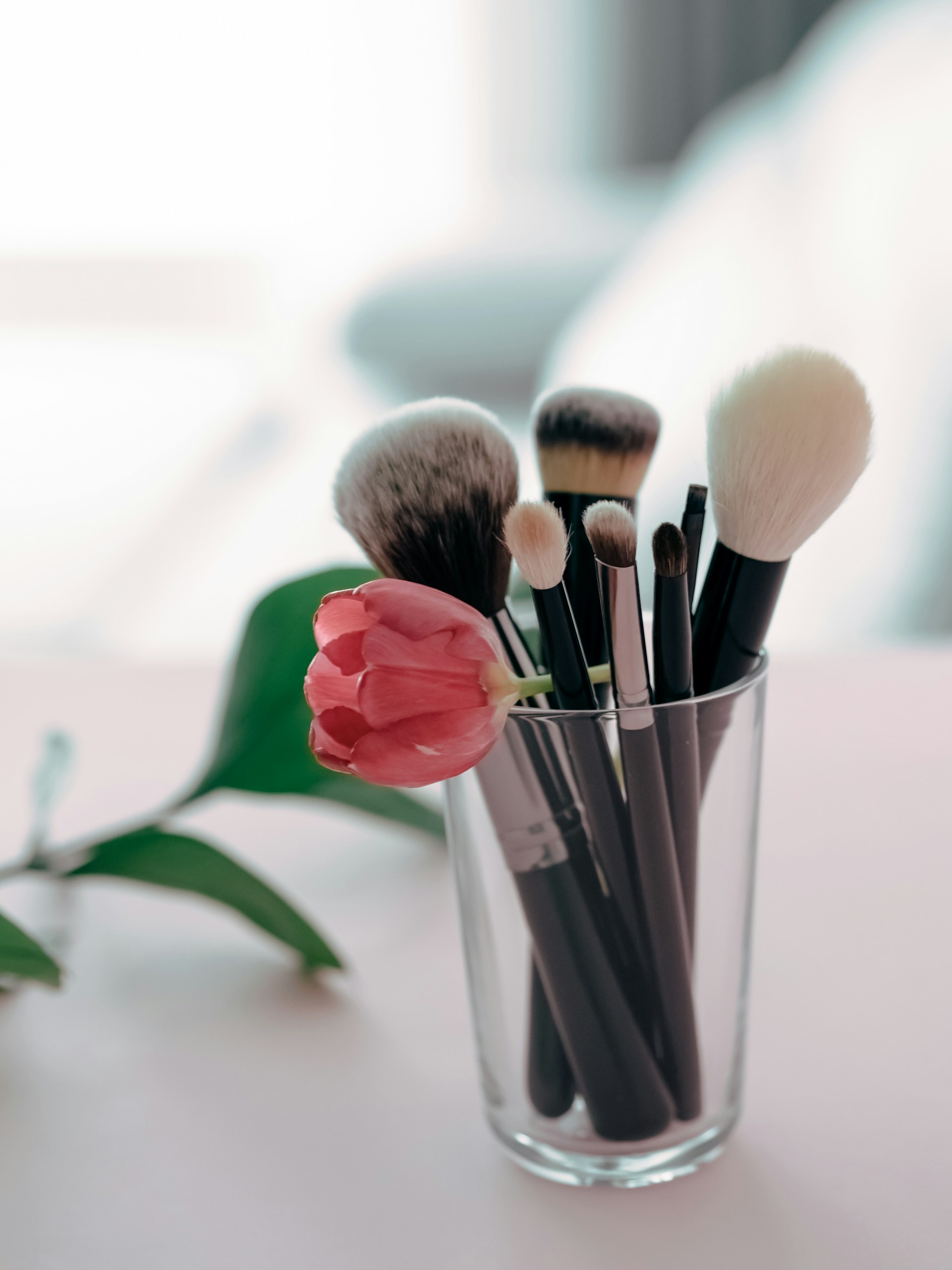 a glass filled with makeup brushes on top of a table
