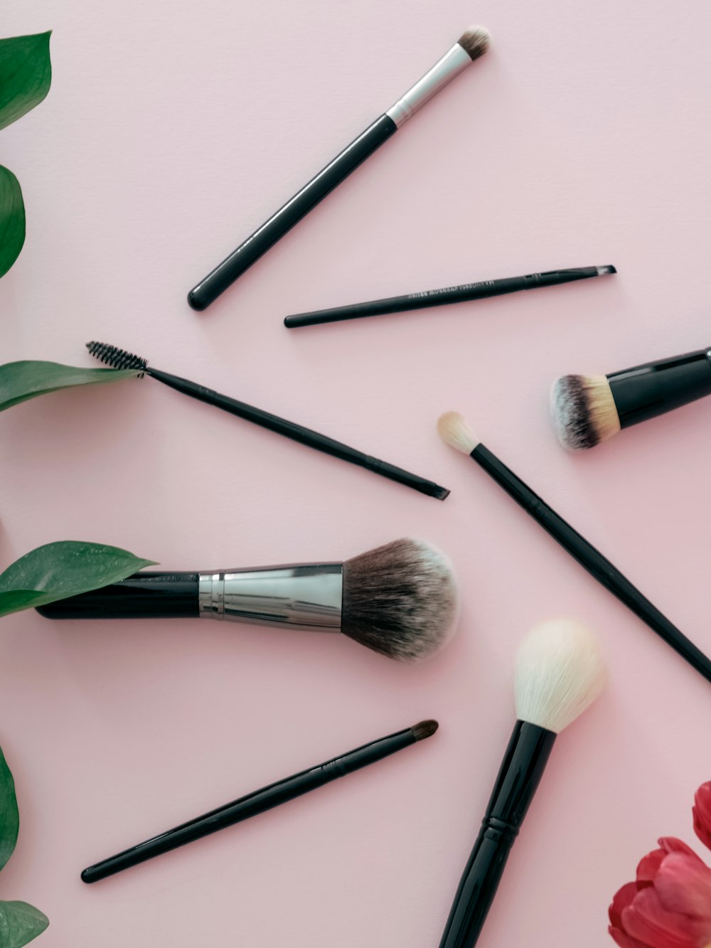 a bunch of makeup brushes sitting on top of a pink surface