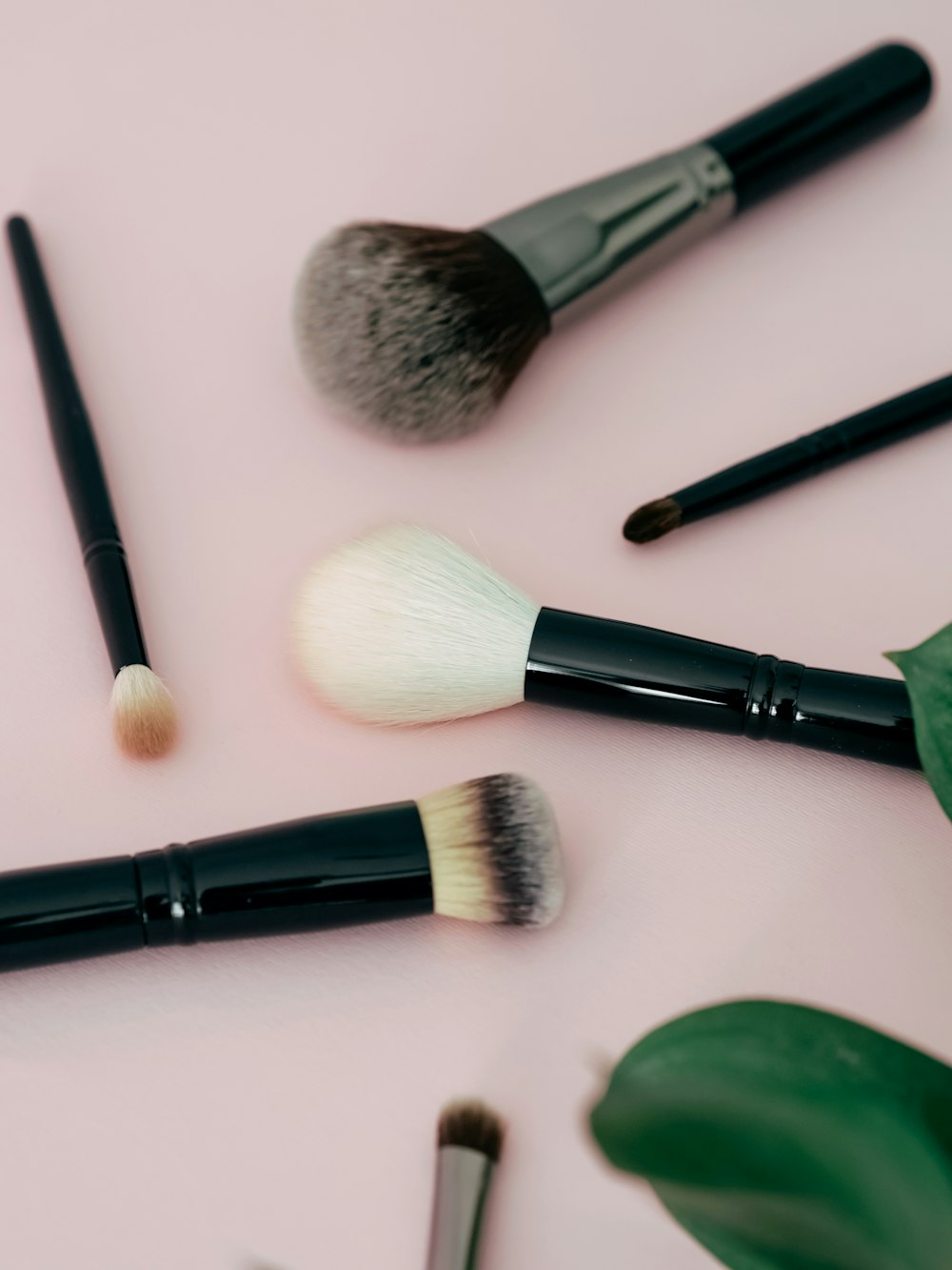 a close up of makeup brushes on a pink surface