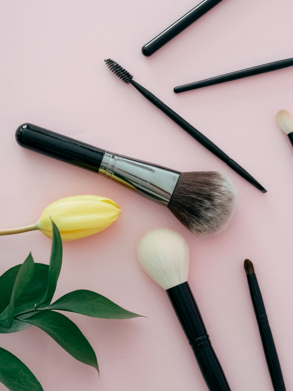 a bunch of makeup brushes sitting on top of a pink surface