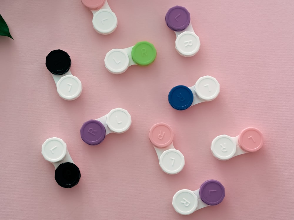 a group of different colored buttons on a pink surface