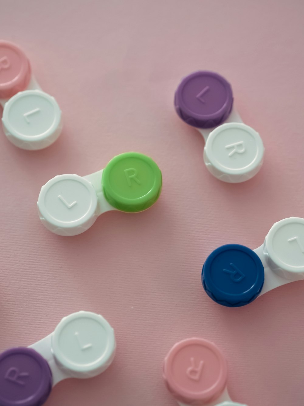 a group of different colored buttons on a pink surface