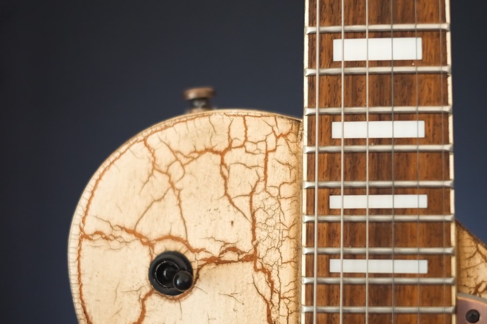a close up of a guitar neck with a guitar in the background