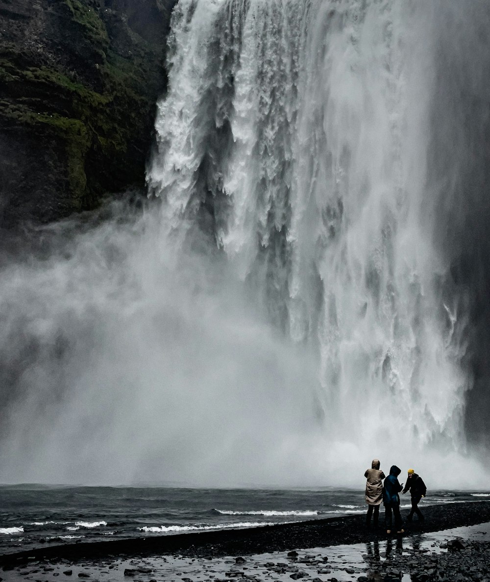 a group of people standing in front of a waterfall