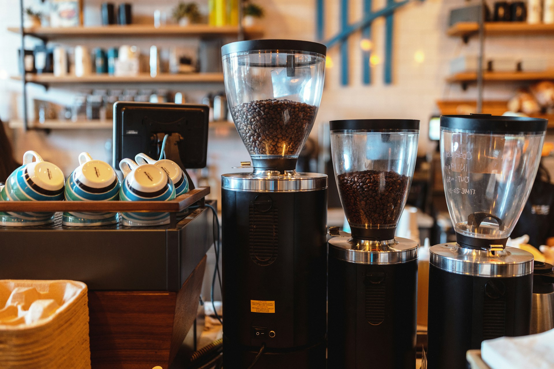 An inviting coffee gallery corner featuring a variety of coffee cups and brewing equipment displayed on shelves with warm lighting.