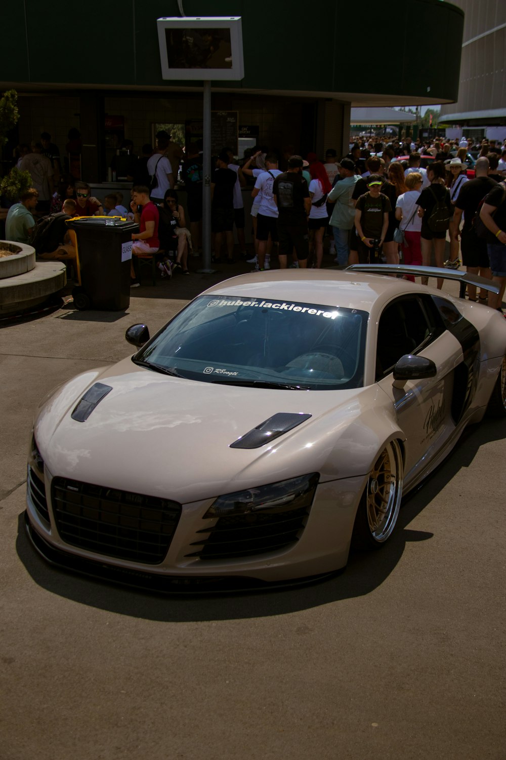 a white sports car parked in front of a crowd of people