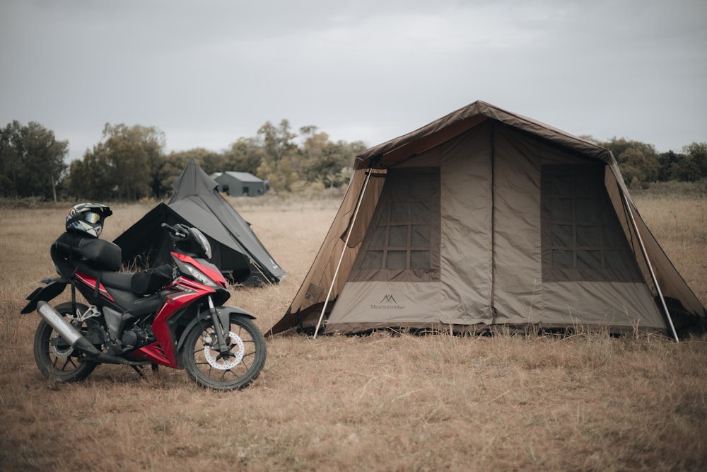 ein Motorrad, das neben einem Zelt auf einem Feld geparkt ist