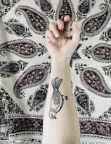 Close-up of a detailed black and gray tattoo on forearm showing fine line work.