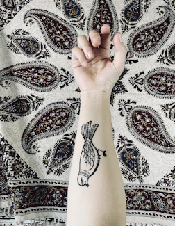 Abstract watercolor tattoo with splashes of color on forearm