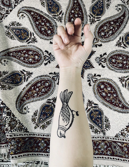 A wrist adorned with a small tattoo of traditional Portuguese azulejos patterns