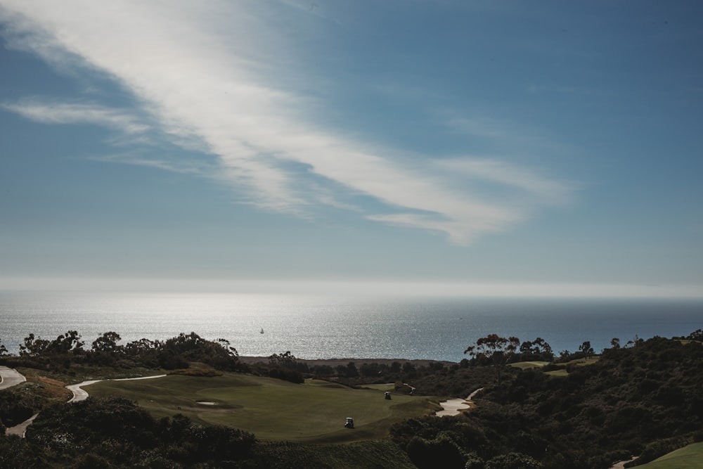 a scenic view of a golf course and the ocean