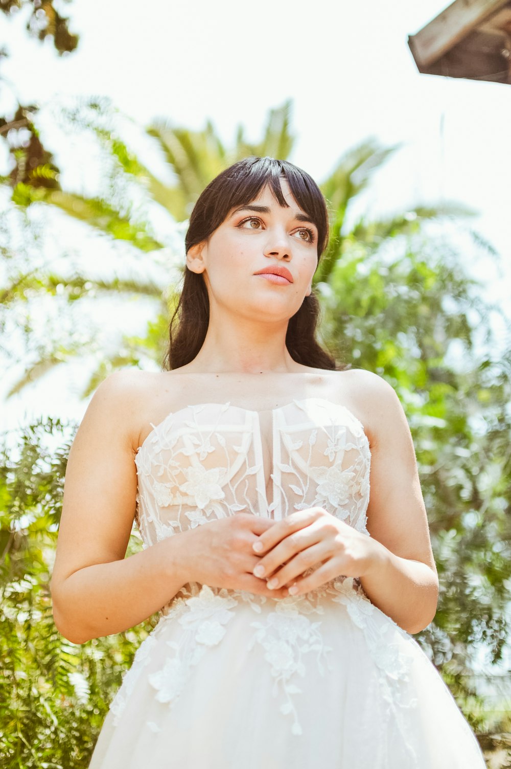 a woman in a wedding dress standing in front of trees