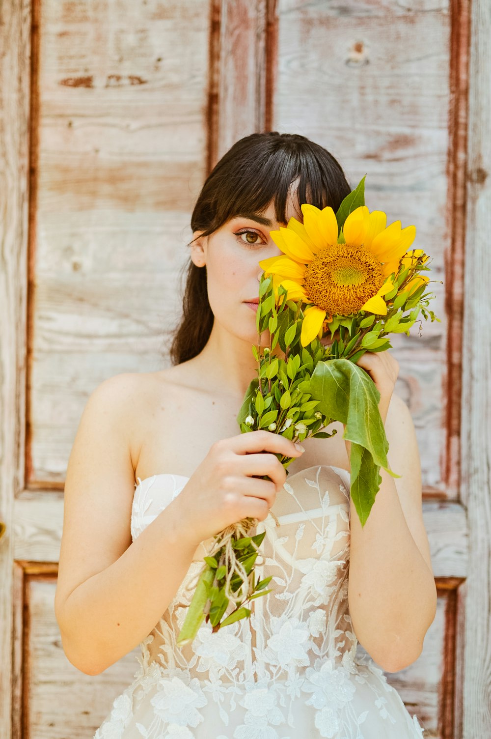 a woman in a wedding dress holding a bouquet of sunflowers