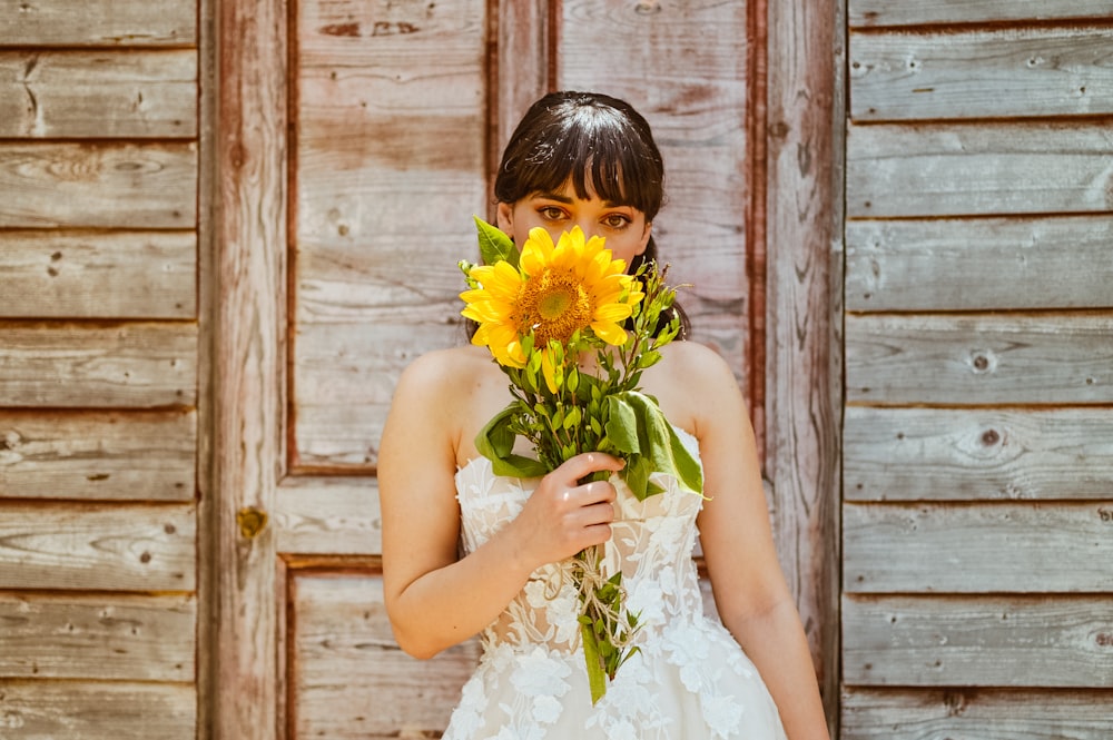 a woman in a wedding dress holding a bouquet of sunflowers