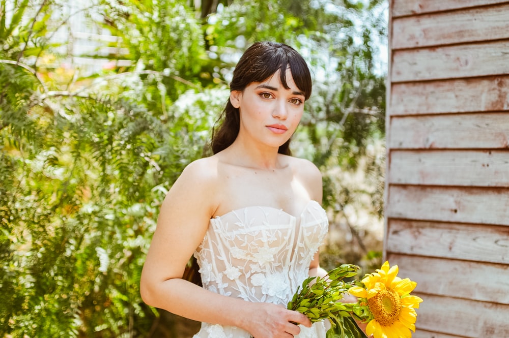 a woman in a wedding dress holding a bouquet of sunflowers