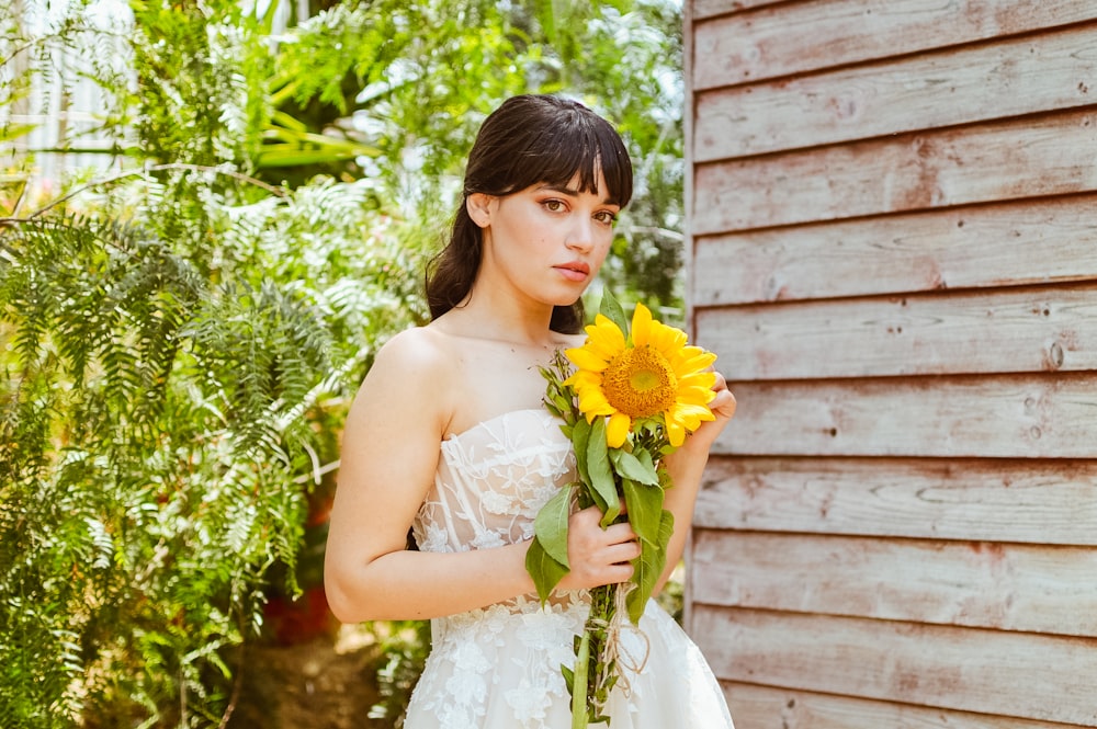 a woman in a wedding dress holding a bouquet of sunflowers