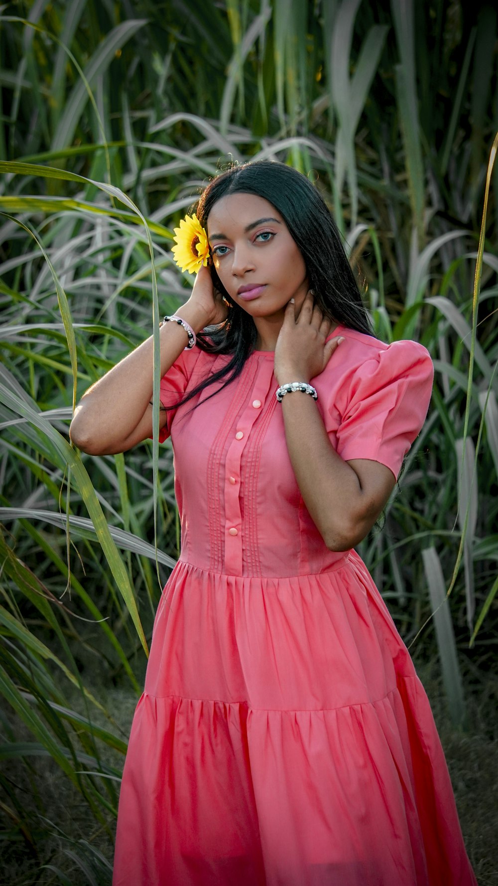 a woman in a pink dress holding a yellow flower