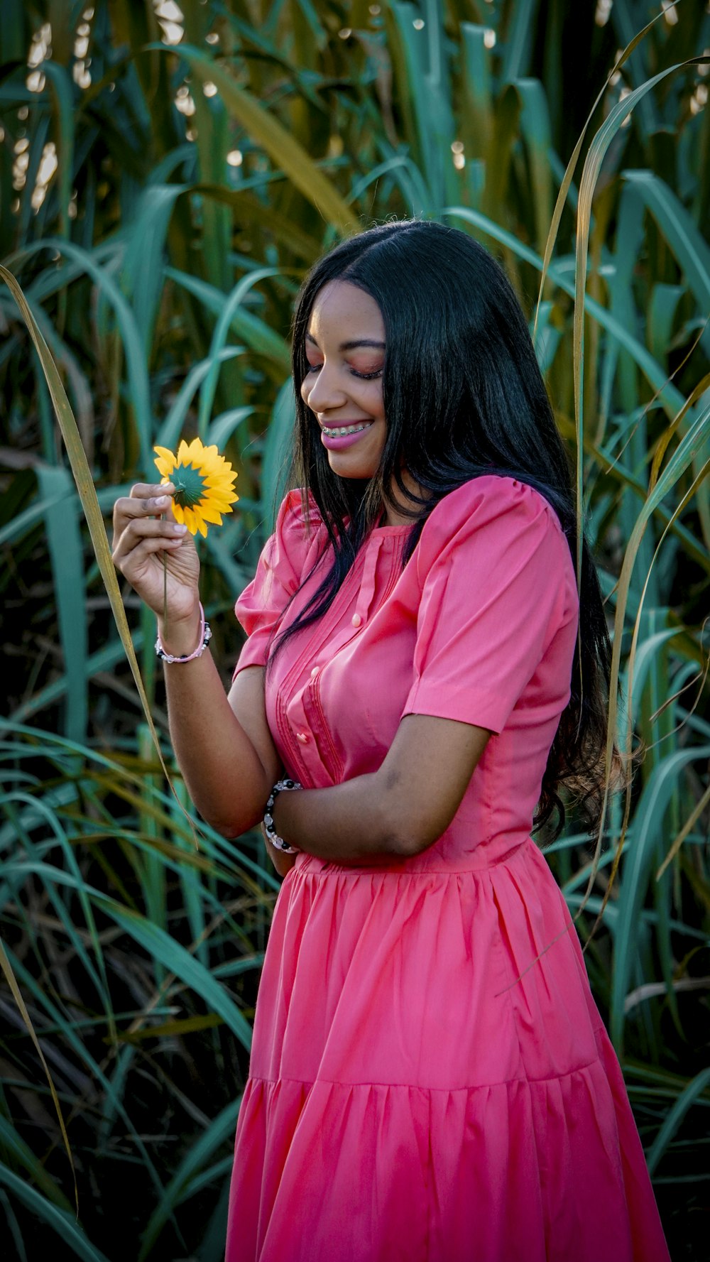 a woman in a pink dress holding a yellow flower