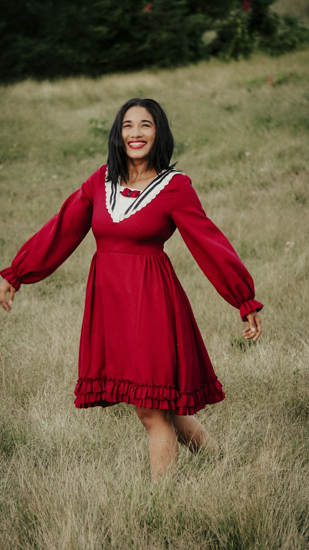 a woman in a red dress standing in a field