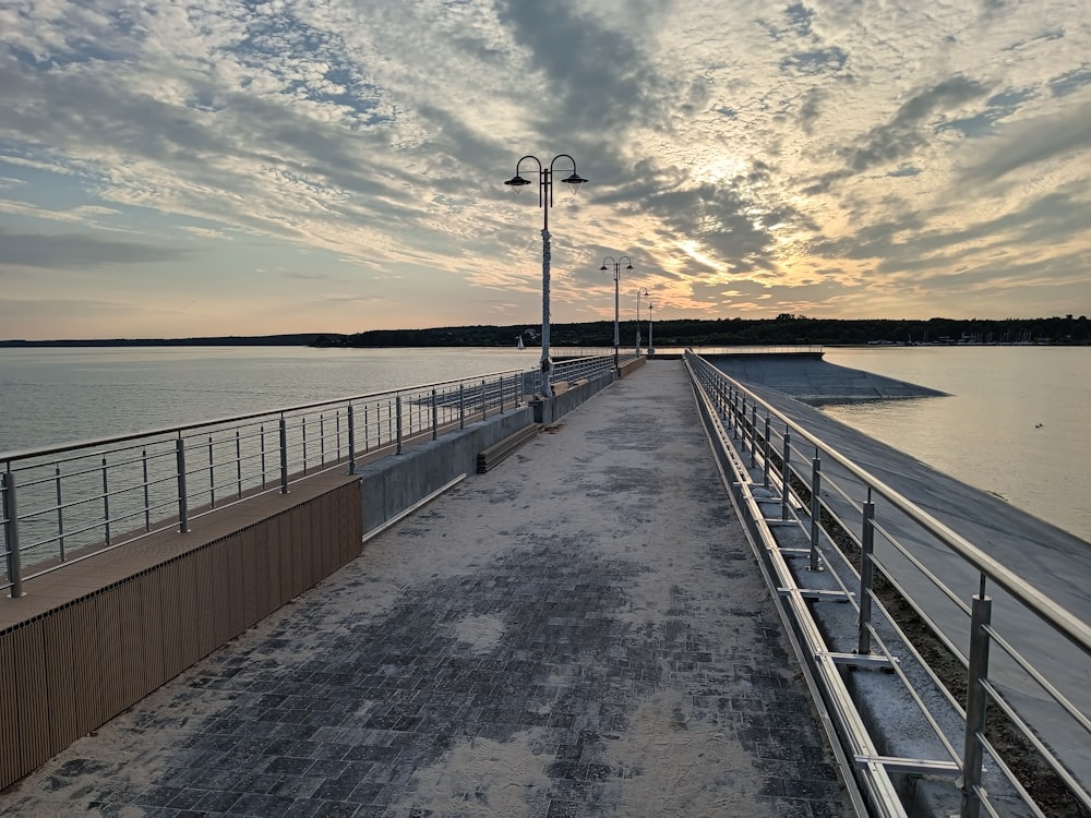 the sun is setting over the water on the pier