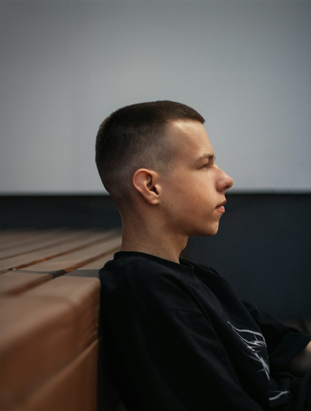 a young man sitting on a bench looking off into the distance