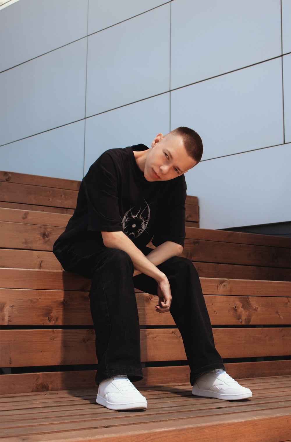 a man sitting on a wooden bench next to a wall