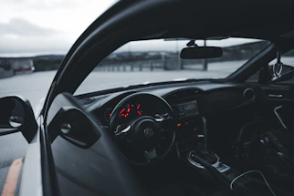 A sleek luxury car dashboard illuminated by red ambient lighting at night.
