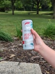 Person holding an energy drink outdoors during sunrise
