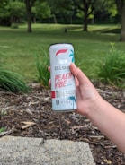Person holding an energy drink outdoors during sunrise